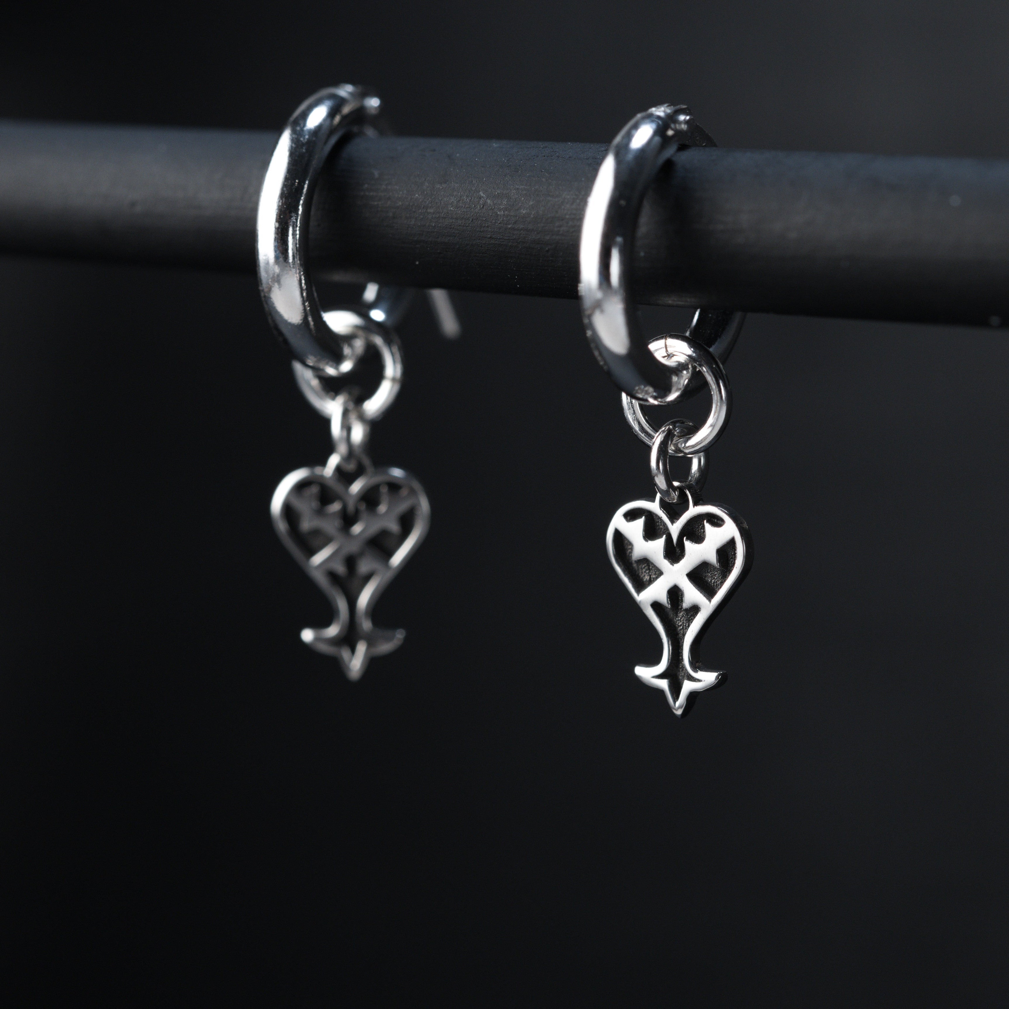 Kage Earrings de aro puestos, mostrando un diseño sutil y oscuro de corazón invertido