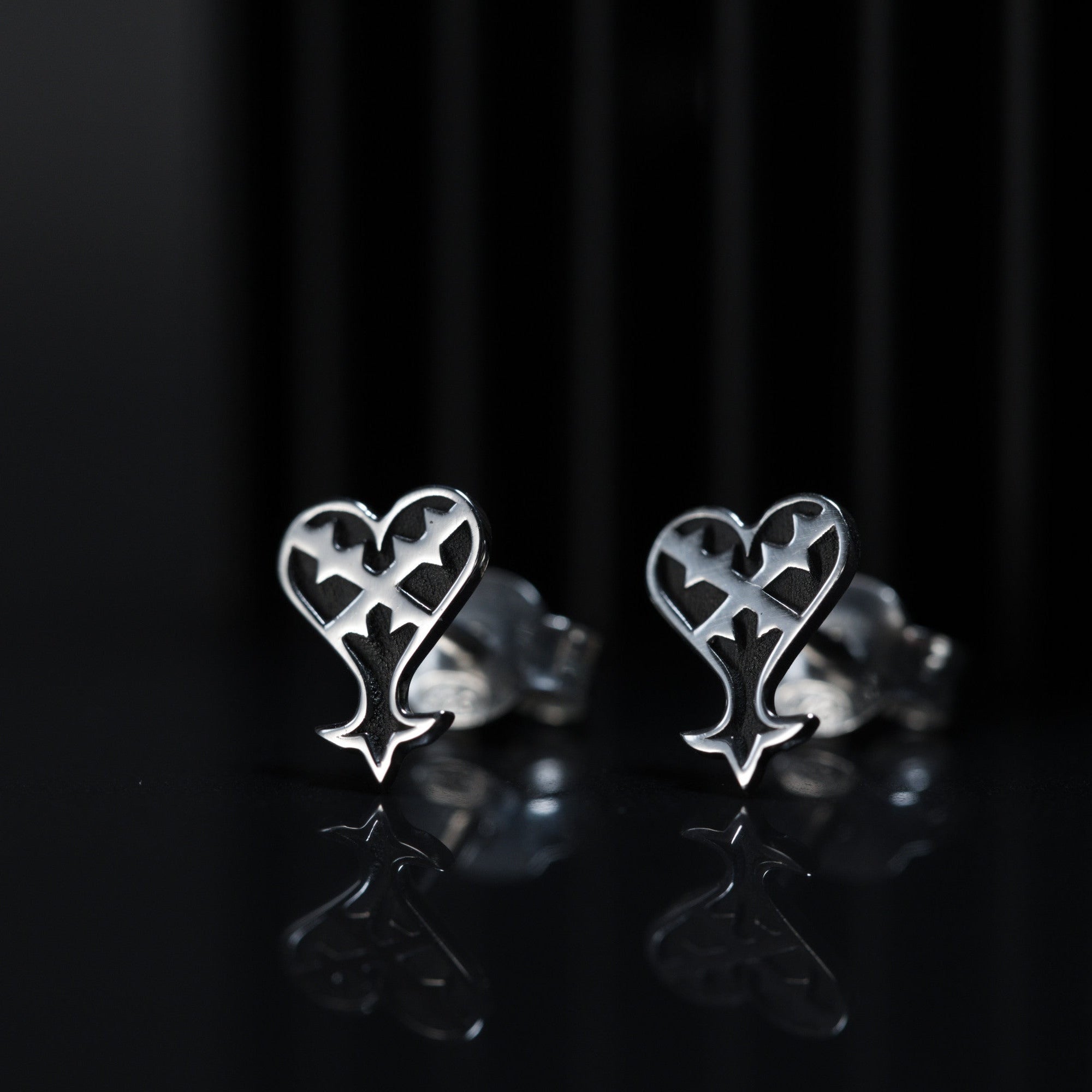 Detalle de Kage Earrings de presión mostrando el diseño de corazón invertido en plata de ley