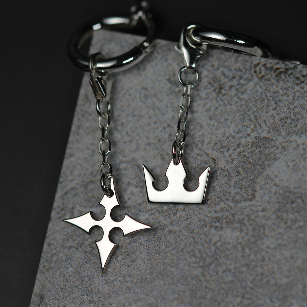 Detalle de Korona Earrings de cadena mostrando charms de corona y cruz unidos por una cadena fina