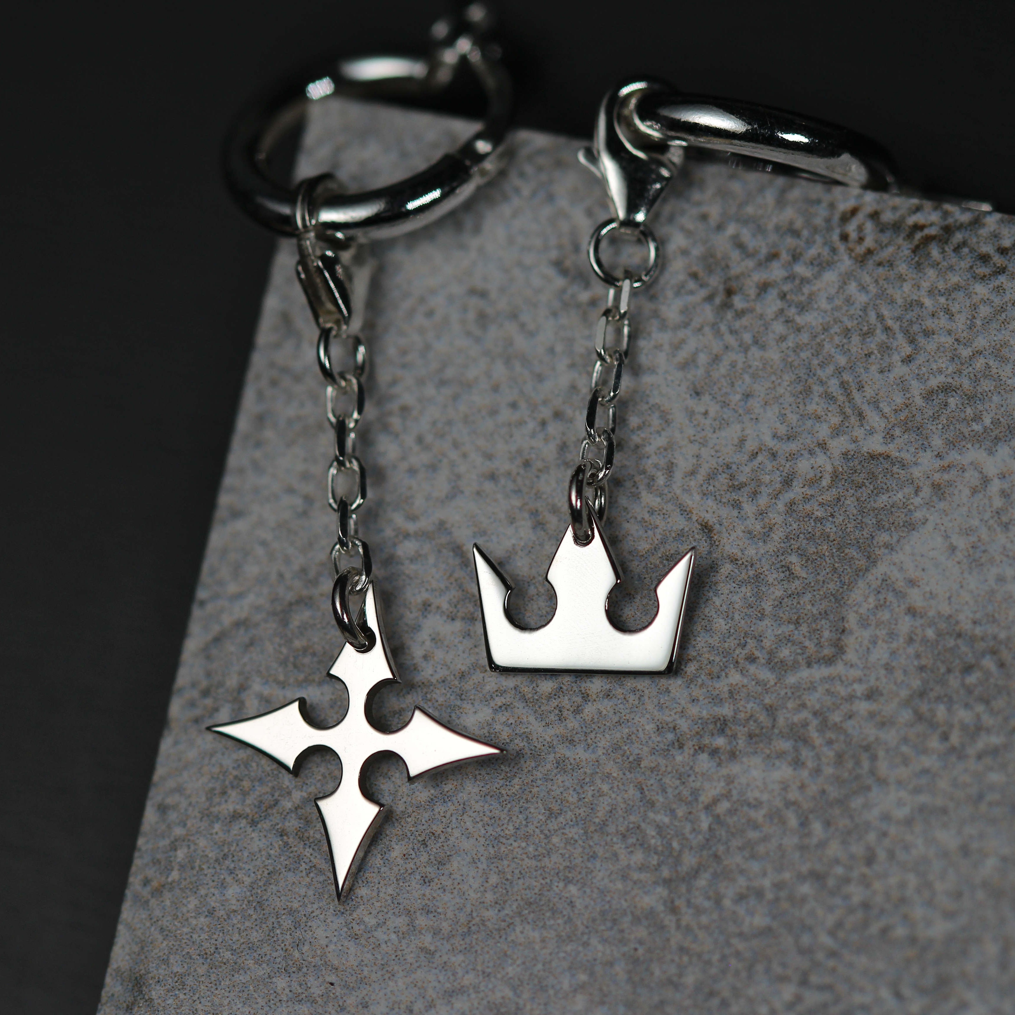 Detalle de Korona Earrings de cadena mostrando charms de corona y cruz unidos por una cadena fina
