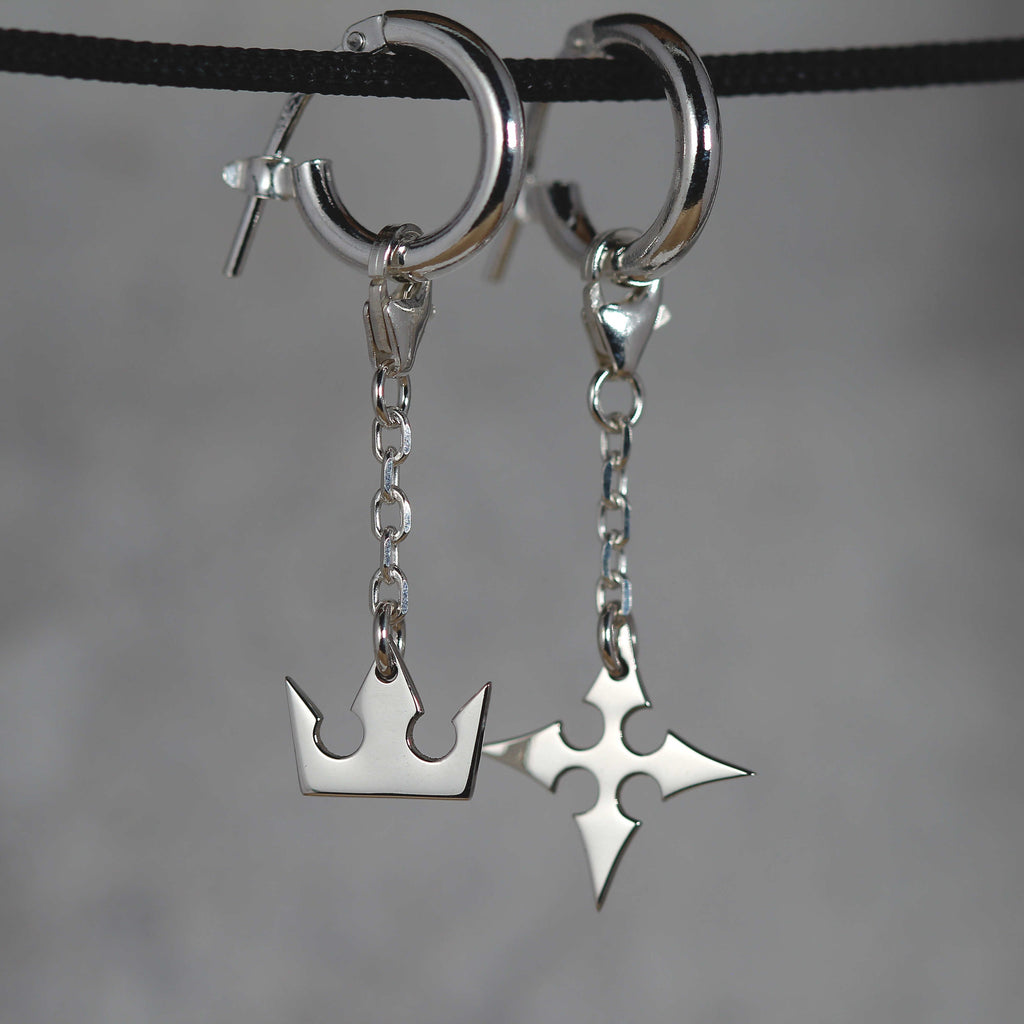 Korona Earrings de cadena puestos, mostrando movimiento y una elegante conexión de cadena entre el aro y los charms