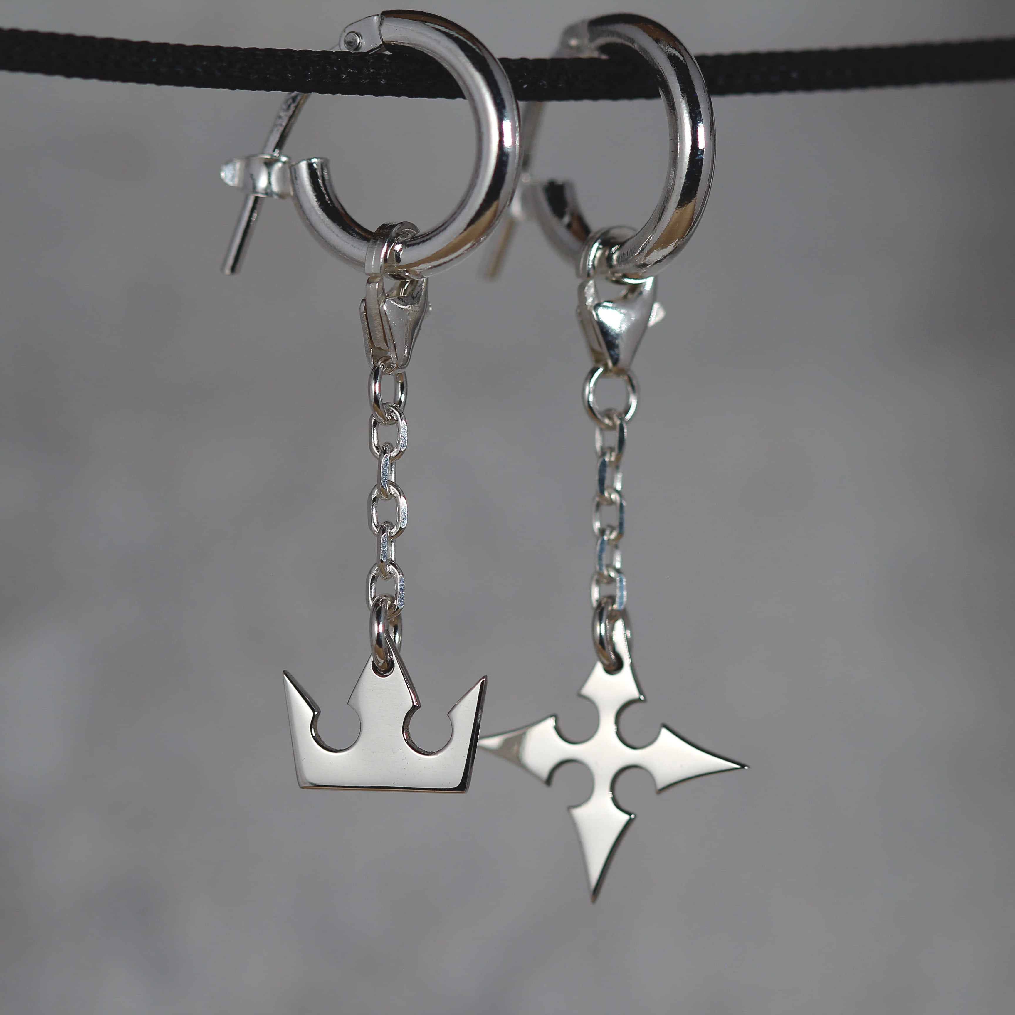 Korona Earrings de cadena puestos, mostrando movimiento y una elegante conexión de cadena entre el aro y los charms