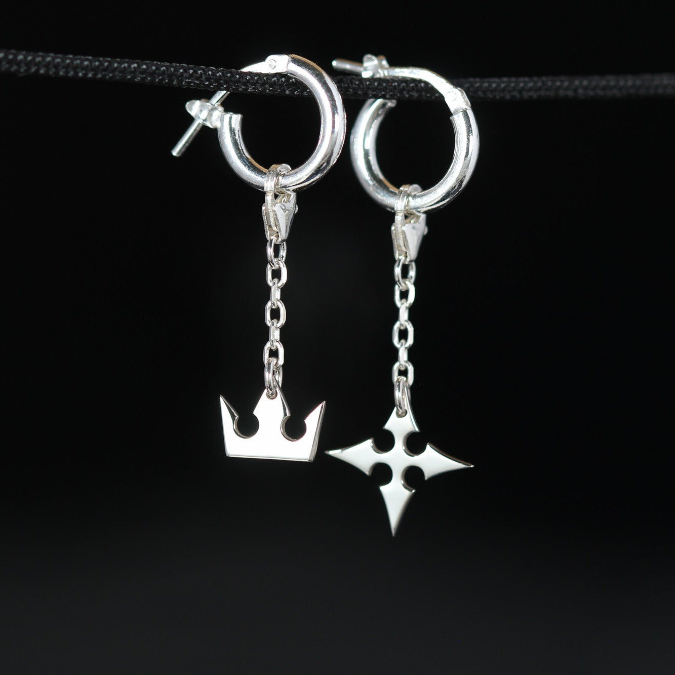 Korona Earrings de cadena en plata de ley con símbolos de corona y cruz unidos por una cadena delicada