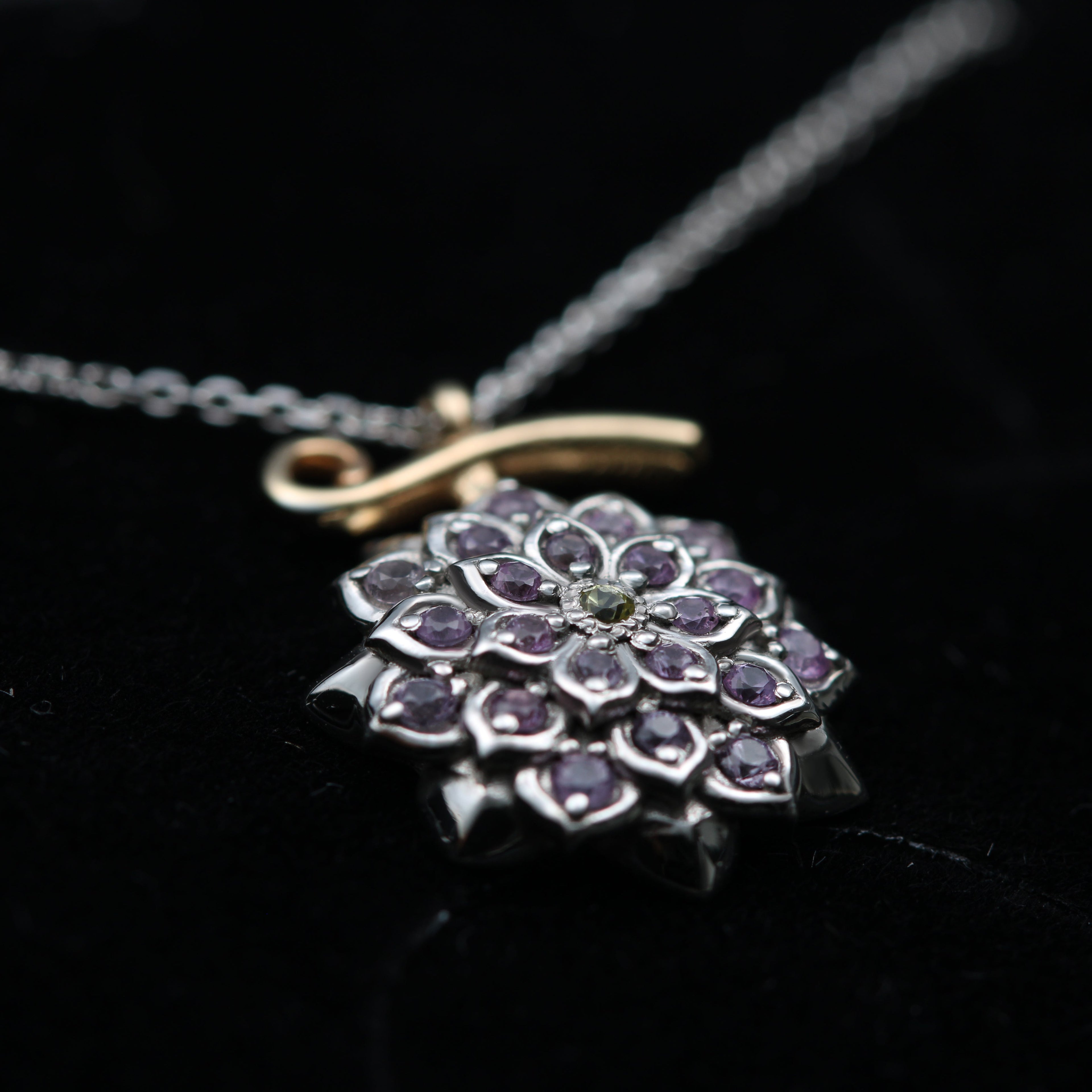 Detalle de los zafiros lilas y amarillos en el colgante de fruta floral